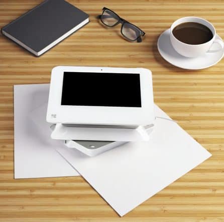 Mobile point of sale terminal for payment processing on a wooden desk with a coffee cup and note.
