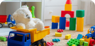 Soft white teddy bear toy on a toy truck surrounded by colorful building blocks and toys.
