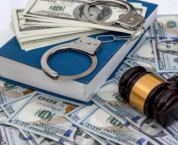 Handcuffs and gavel on money and legal documents for criminal justice and law enforcement themes.