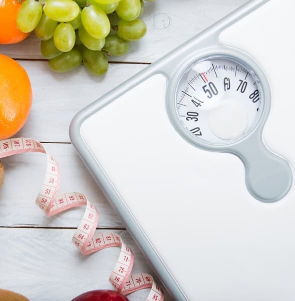 Digital bathroom scale with fruits and measuring tape, health and weight management concept.