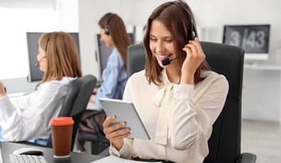 Customer support representative assisting callers at a modern call center.
