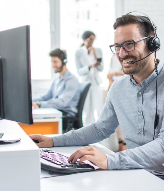 Call center agent with headset working at computer for Customer Service support.