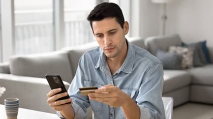 Seated man using smartphone for payment processing or business management.