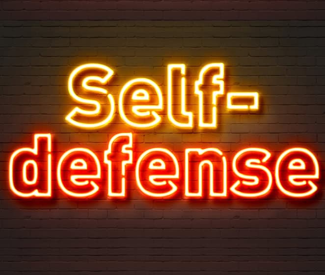 Self-defense neon sign on brick wall, empowering safety and security concepts.