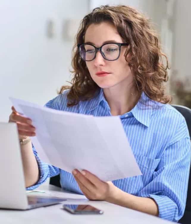Efficient professional woman reviewing financial documents at work, emphasizing business and payment solutions.