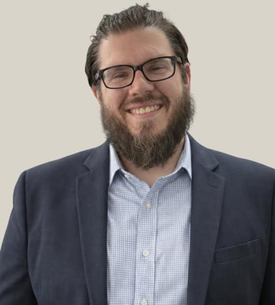 Efficient payment processing expert with glasses and beard, smiling in a professional suit.
