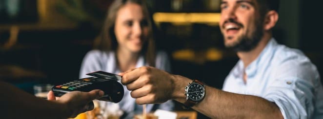 POS credit card payment transaction at restaurant, customer paying bill, friendly service.