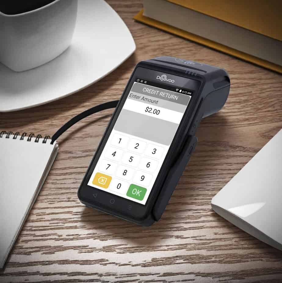 Mobile credit card reader for Host Merchant Services on wooden desk with coffee and notebooks, showcasing payment processing solution.