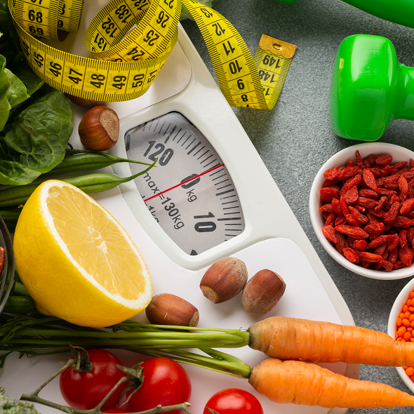 Apple and orange with measuring tape on a notebook, symbolizing health and measurement.
